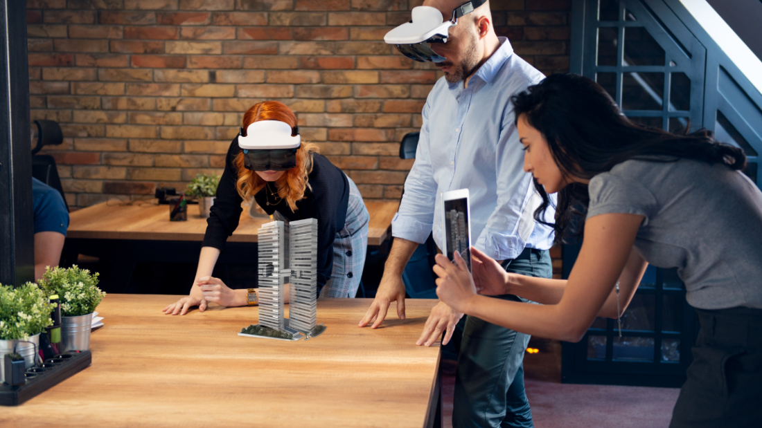 Kuvakaappaus ARVET-hankkeen www-sivulta, kuvassa yksi henkilö kuvaa esinettä ja kaksi henkilöä seuraa vierestä VR-lasit päässä.