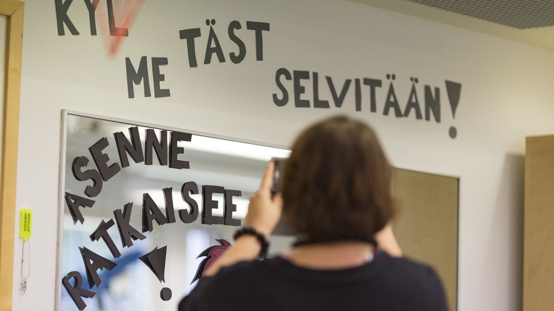 Oven yläpuolelle ja oveen kirjoitettu ipaperisilla kirjaimilla "Kyl me tästä selvitään! Asenne ratkeisee!"