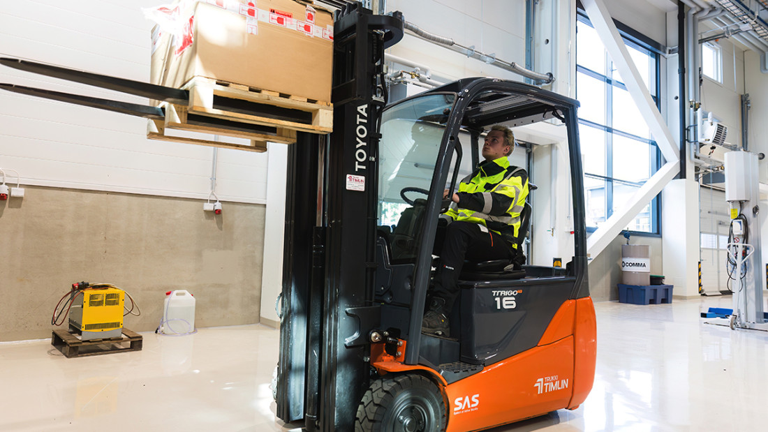 Opiskelijan nostaa keskittyneesti laatikkoa trukilla.