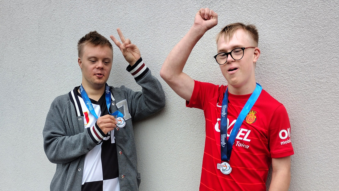 Eelis ja Ukko mitalit-kaulassa ja nostavat käsiään voiton merkiksi.