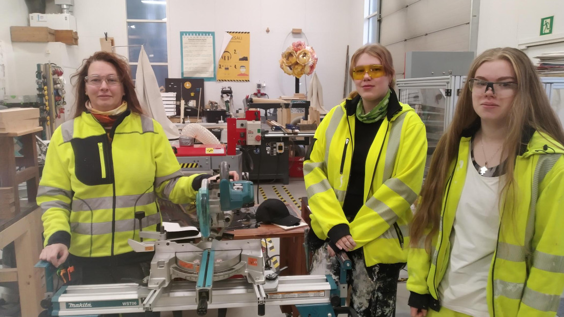 Opettaja ja kaksi opiskelijaa työsalissa.