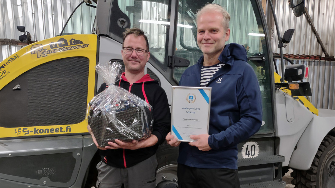 Kaksi miestä poseeraa kameralle trukin edessä.