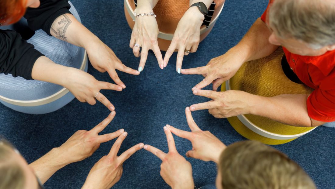 Ihmisiä, jotka pitävät etusormiaan ringissä muodostaen suuren tähden.