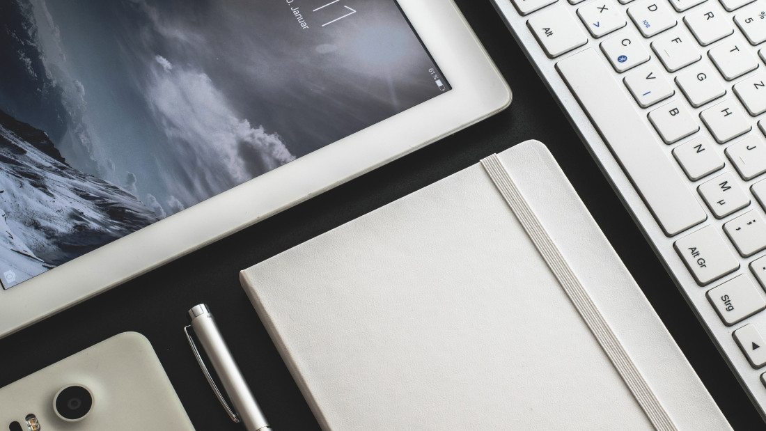 Kuvituskuva, jossa tabletti, puhelin, kynä, näppäimistö ja muistilehtiö.