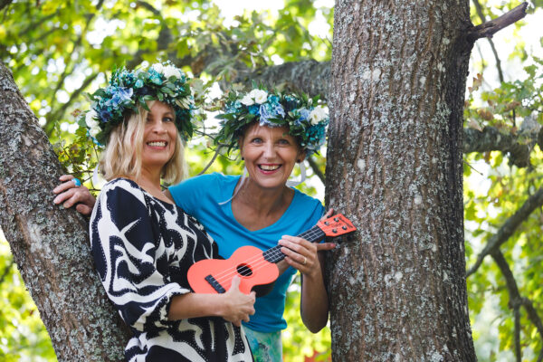 Tuula Niskanen ja Virpi Jussila ovat puussa ja soittavat kitaraa.
