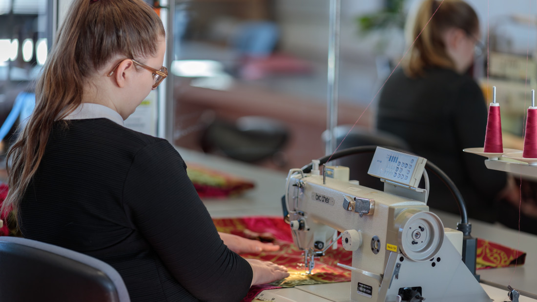 Opiskelija ompelee ompelukoneella.