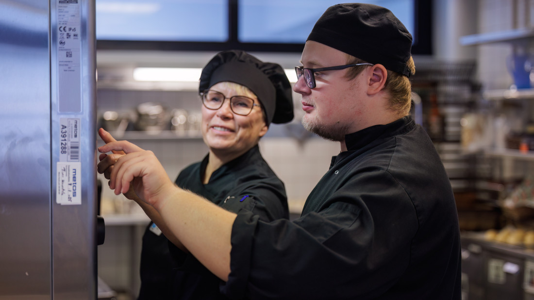 Opettaja ohjaa opiskelijaa suurtalouskeittiössä.