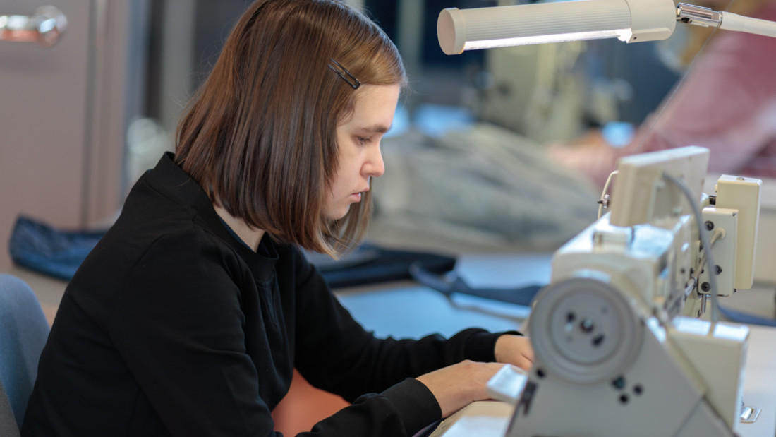 Opiskelija ompelee ompelukoneella.