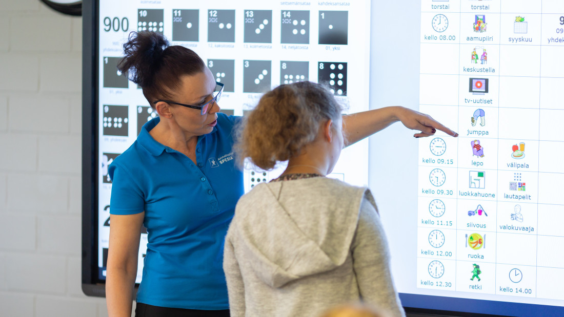 Opettaja näyttää opiskelijalle aikataulua.
