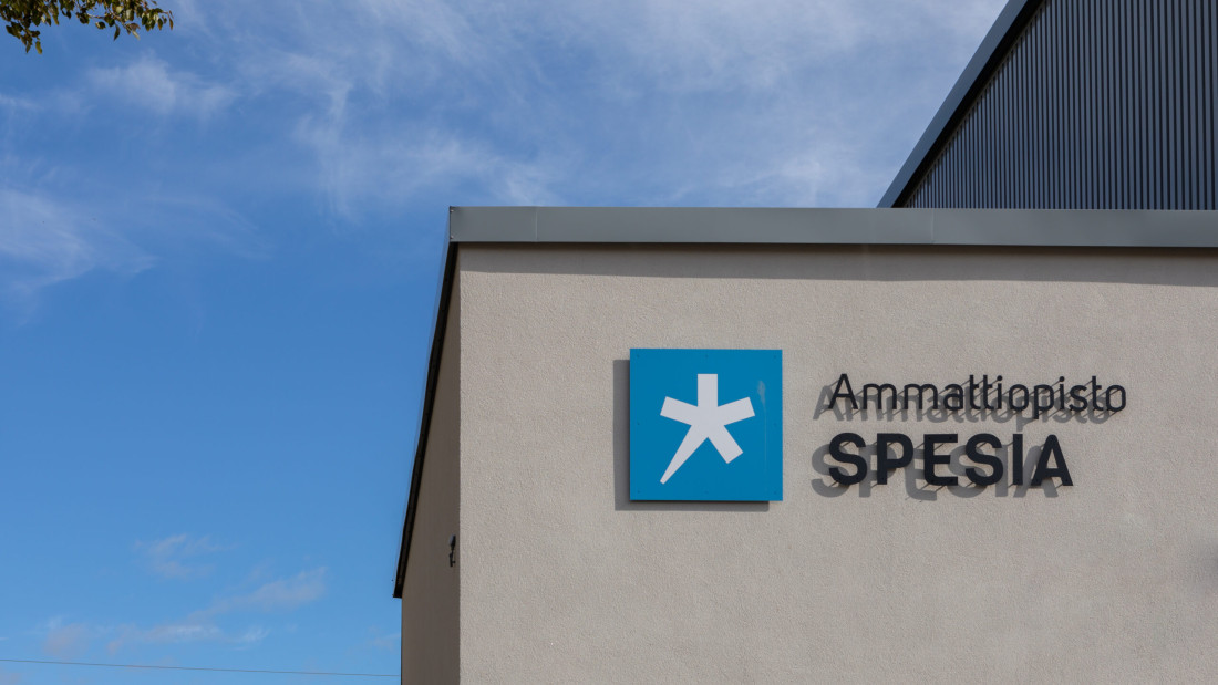 Ammattiopisto Spesia -kyltti rakennuksen seinällä, taustalla sininen taivas.