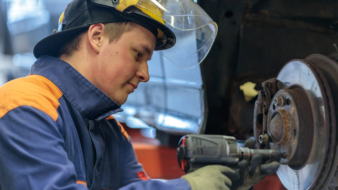 Opiskelija korjaa autoa.