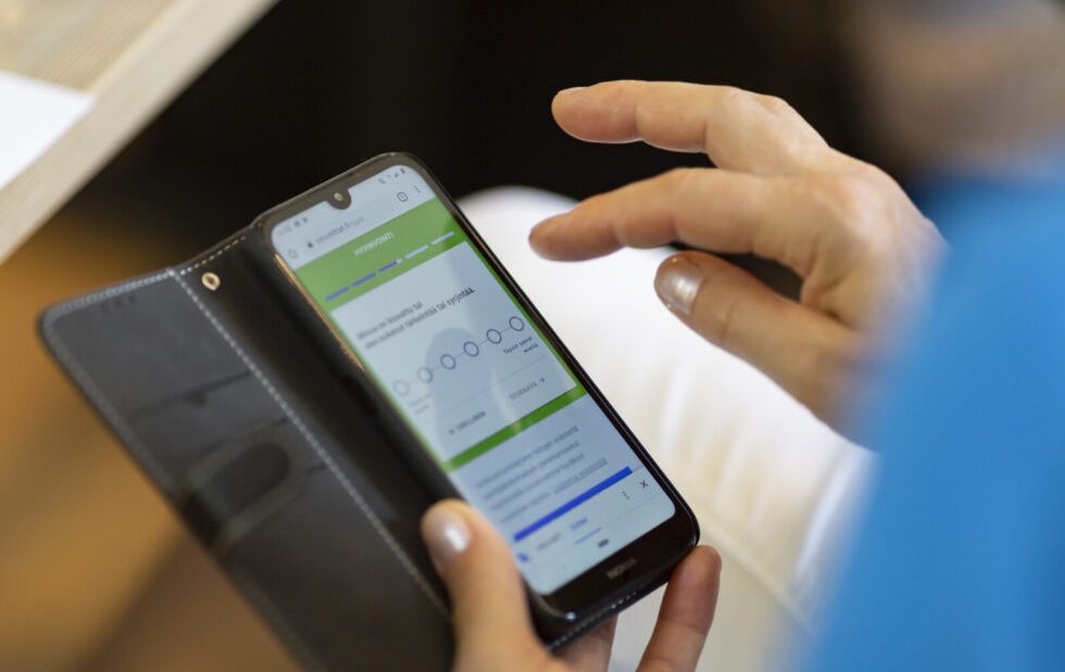 Henkilö tutkii taulukkoa kännykästään.