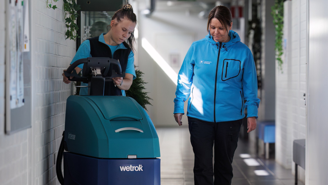 Ohjaaja neuvoo opiskelijaa, joka ohjaa lattianpesukonetta.