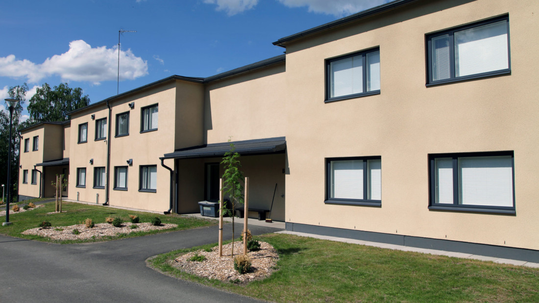 Vaaleanruskea kaksikerroksinen kerrostalo kvätauringossa.
