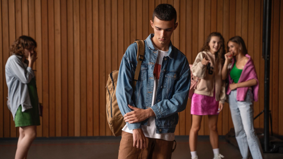 Etualalla allapäin oleva poika, takana ihmiset kuiskuttelevat ja osoittelevat.