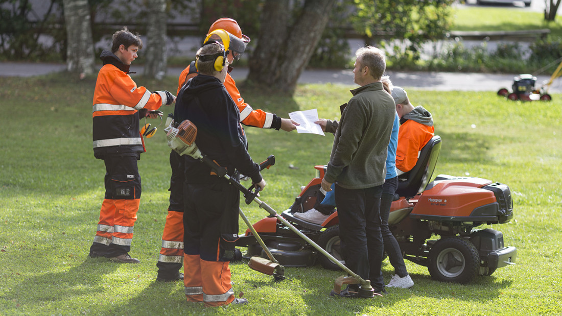 Opettaja neuvoo kiinteistönhoitajaopiskelijoita, jotka tekevät erilaisia työtehtäviä ulkona.