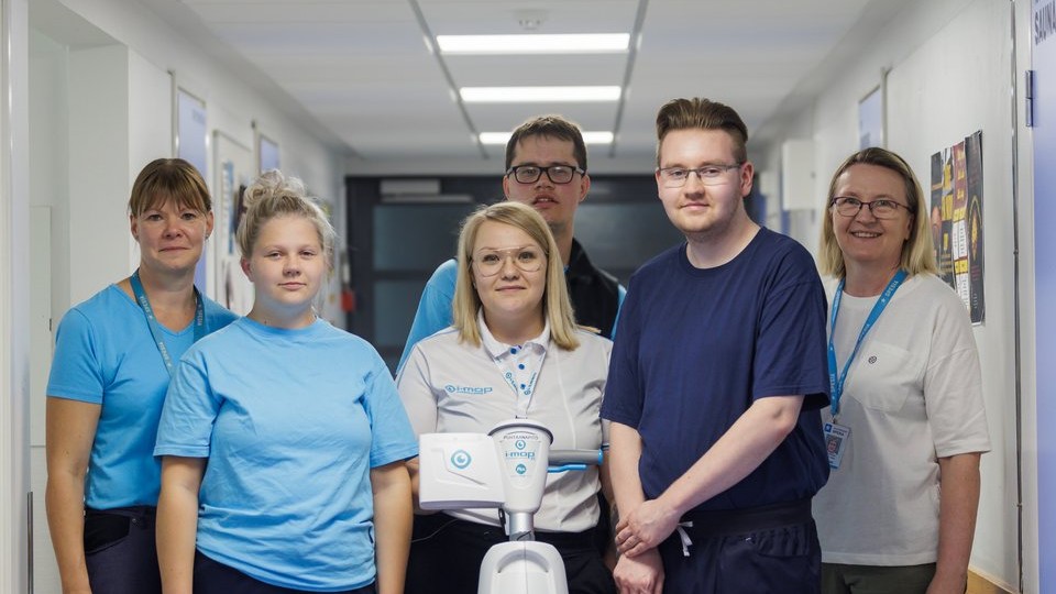 Yhteiskuvassa Spesian opiskelijoita yhdessä opettaja Päivi Hauhtosen ja ohjaajan Merita Valosen sekä robotiikan asiantuntijan ja kouluttajan Anniina Niemisen kanssa. Kuvan keskellä puhtausalan robotti.