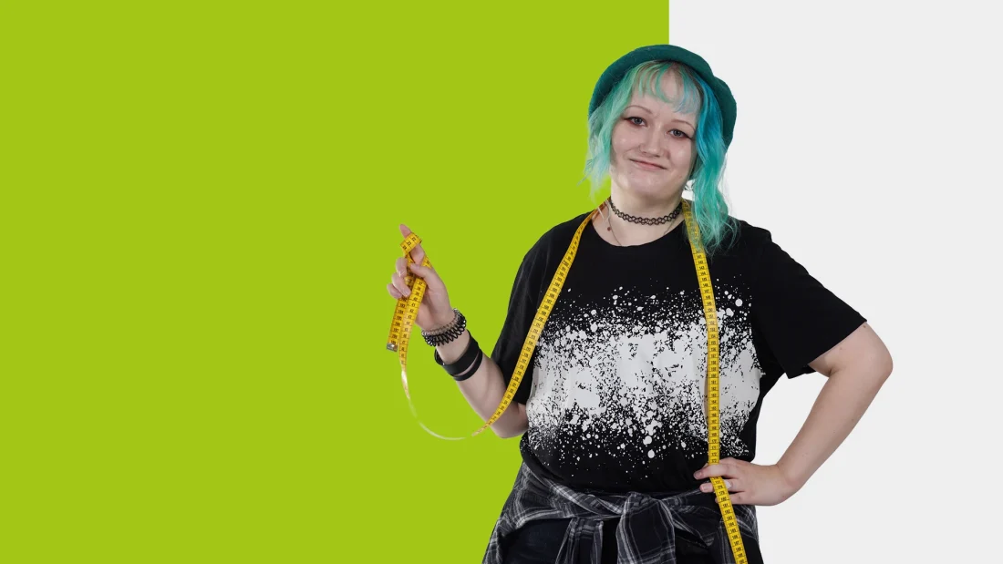 Turkoositukkainen nuori nainen mittanauha kaulassa.