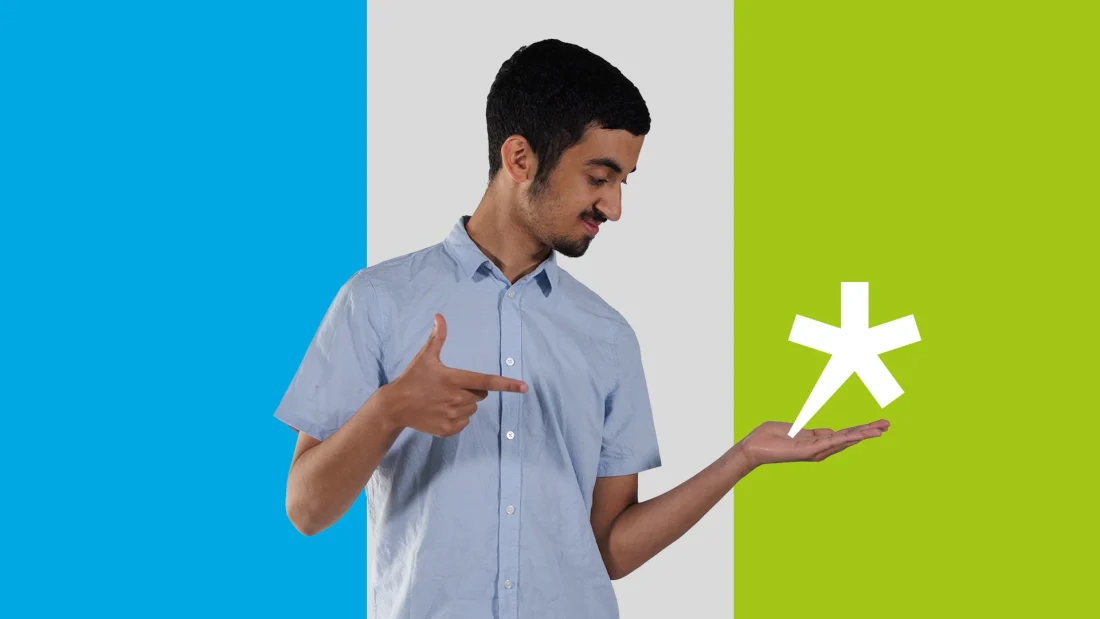 Nuori mies katsoo sivulle, pitäen toista kättä kuin pitelisi siinä jotain ja osoittaa toisella kädellä pitelemäänsä asiaa.