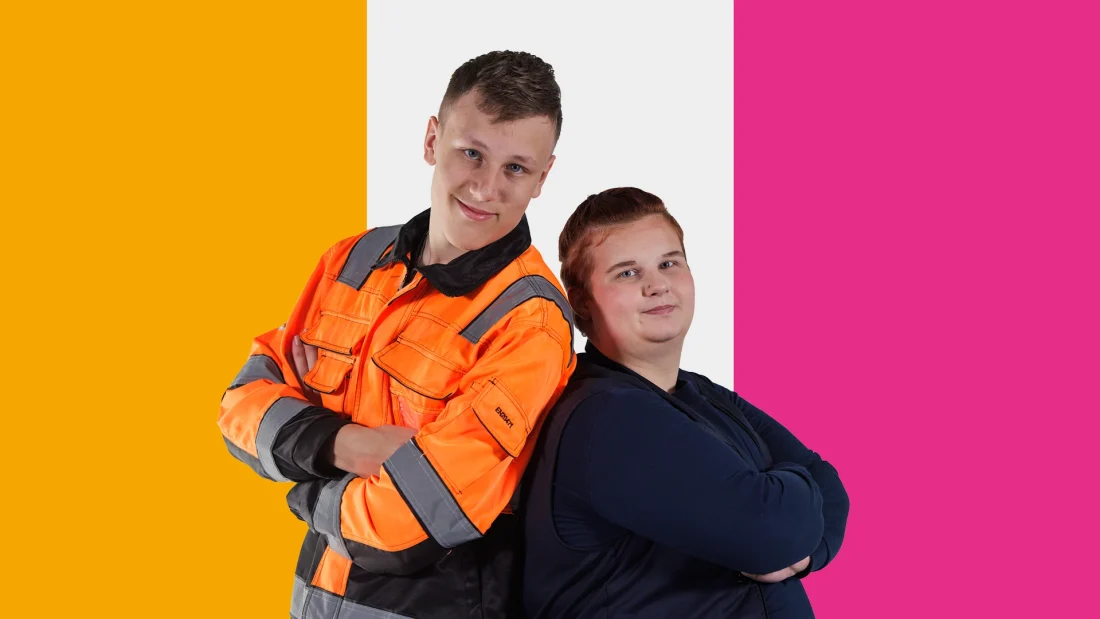 Kaksi nuorta seisoo selät vastakkain ja kädet puuskassa, päällään työvaatteet.