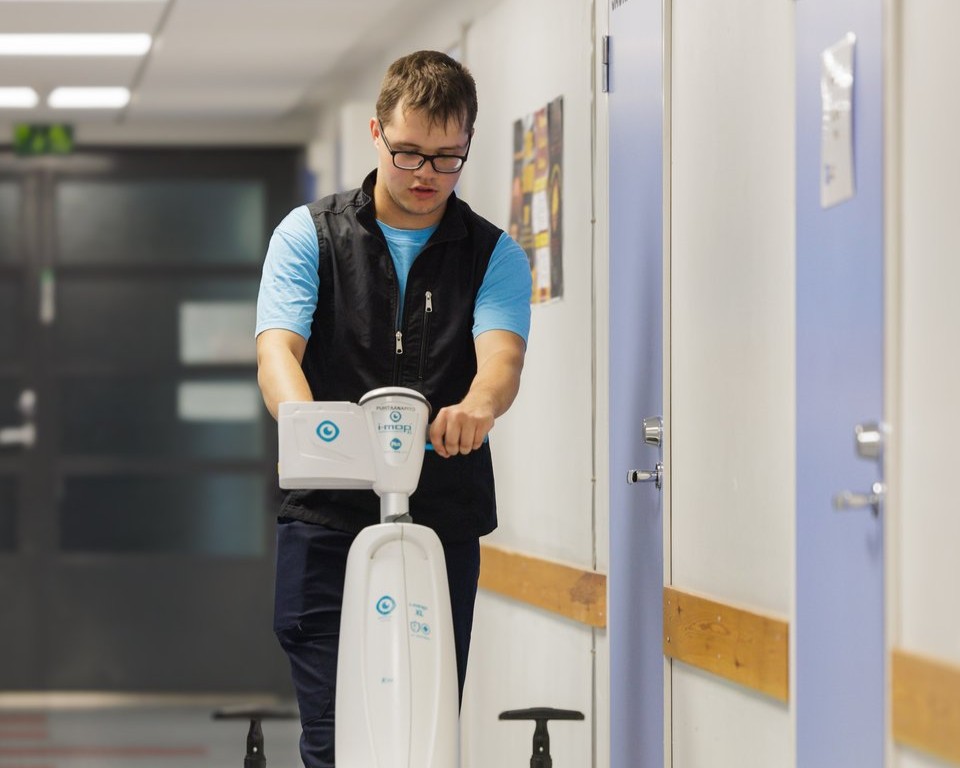 Nuori siivoaa käytävää puhtausalan robotilla.