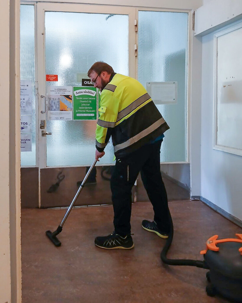 Spesian opiskelija Joonatan imuroi käytävää työvaatteet yllään.