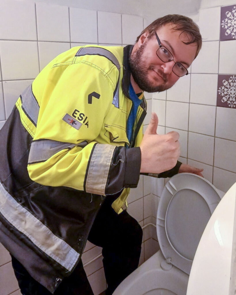 Spesian opiskelija Joonatan näyttää peukkua kameralle tarkastettuaan vessan toiminnan. 