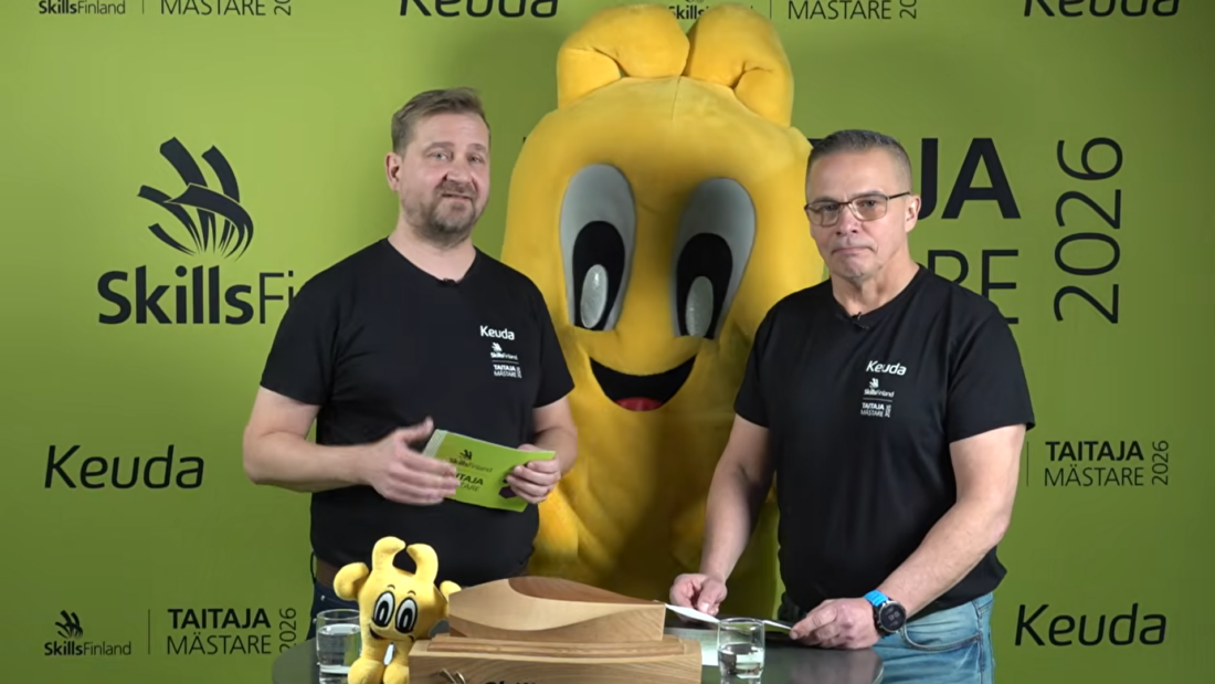 Kaksi miestä ja keltainen Taitaja-maskotti Taitaja- ja SkillsFinland-logojen koristamassa studiossa.