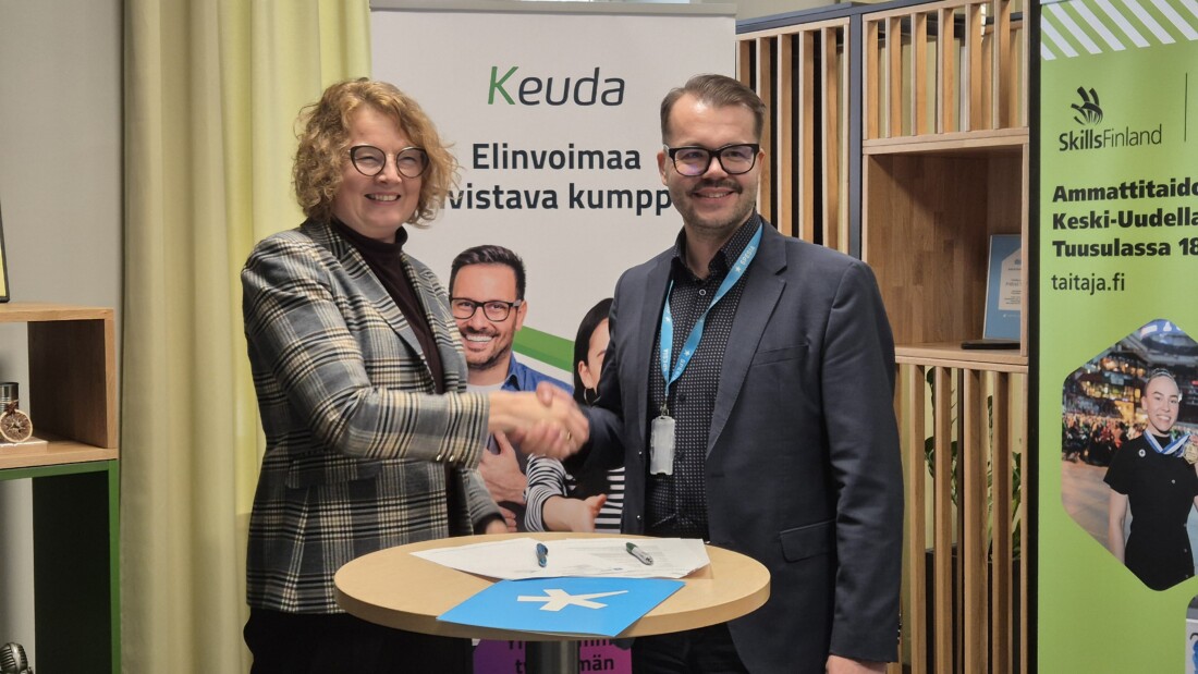 Nainen ja mies kättelevät, seinällä teksti Elinvoimaa vahvistava kumppani.