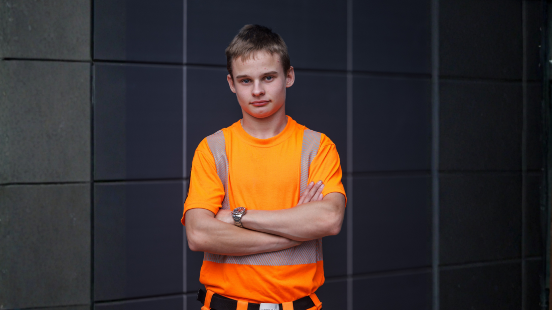 Nuori mies seisoo työvaatteet yllään.