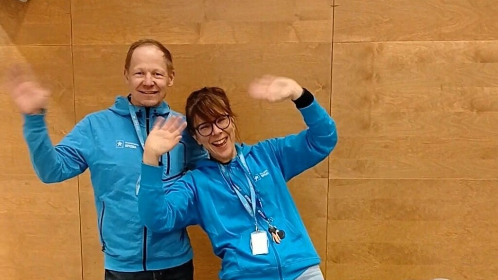 Kaksi henkilöä vilkuttaa iloisesti Spesia hupparit päällään. 