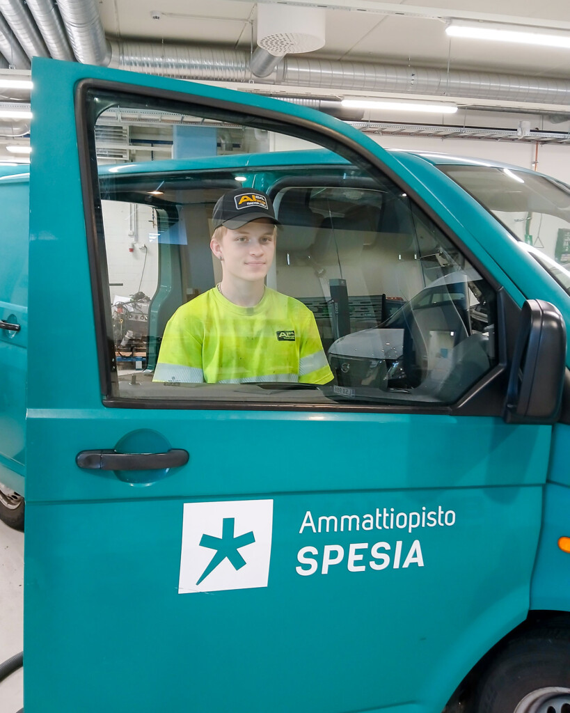 Nuori mies seisoo pakettiauton avatun oven takana ja katsoo ikkunasta. 