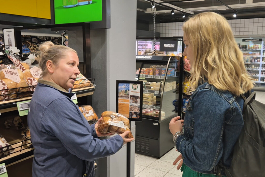 Kaupan työntekijä ja asiakas keskustelevat leipähyllyllä.