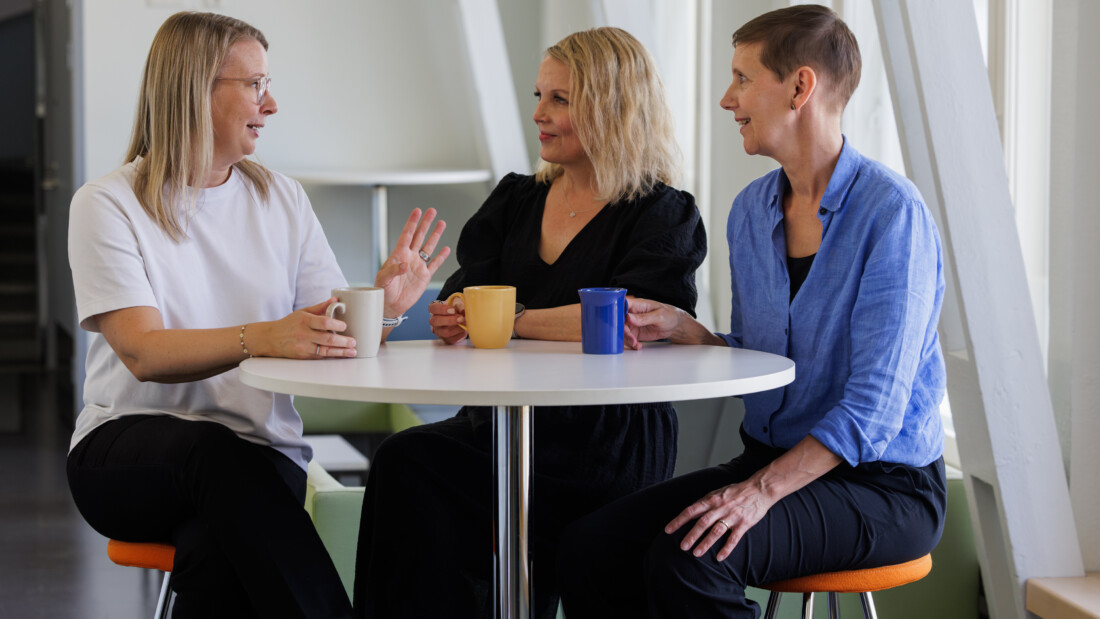 Hanna Halminen, Tuula Niskanen ja Virpi Jussila istuvat pyöreän pöydän äärellä kahvikupit edessään.